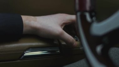 Kolluktaki el, arabanın kapısındaki elektrikli yükseltme mekanizmasının düğmelerine basar. Lüks araba iç mekanı. - Yakın çekim. 4K video.