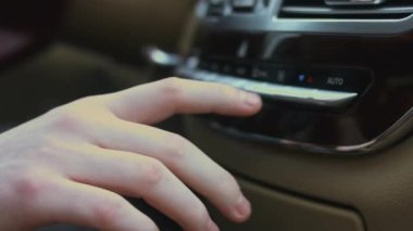 Arabadaki klima düğmesini ayarlamak için elinizi yakın tutun. Otomobil havalandırma sistemi kullanan bir adam. Arabada çift klima kontrolü var. Lüks araba iç mekanı. 4K video.