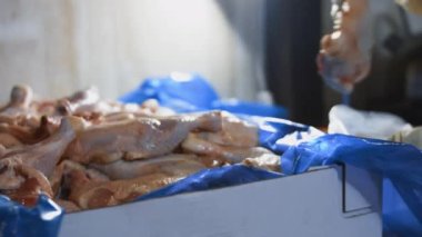 Eldivenli ellerin yakın plan görüntüsü tavuk bacağını bir kutudan ayrı plastik poşetlere paketliyor. Evde daha fazla kullanılmak üzere dondurulmuş etin süreci. 4K video.