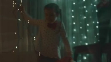 Noel tatili için evlerini dekore eden aile. Güzel mutlu kızlar ışıklarla oynayıp sarılıyorlar. Mutlu Noeller ve mutlu tatiller. Mutlu aile zamanları..