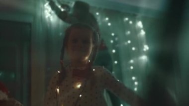 Noel tatili için evlerini dekore eden aile. Güzel mutlu kızlar ışıklarla oynayıp sarılıyorlar. Mutlu Noeller ve mutlu tatiller. Mutlu aile zamanları..