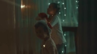 Noel tatili için evlerini dekore eden aile. Güzel mutlu kızlar ışıklarla oynayıp sarılıyorlar. Mutlu Noeller ve mutlu tatiller. Mutlu aile zamanları..
