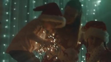 Noel tatili için evlerini dekore eden aile. Güzel mutlu kızlar ışıklarla oynayıp sarılıyorlar. Mutlu Noeller ve mutlu tatiller. Mutlu aile zamanları..