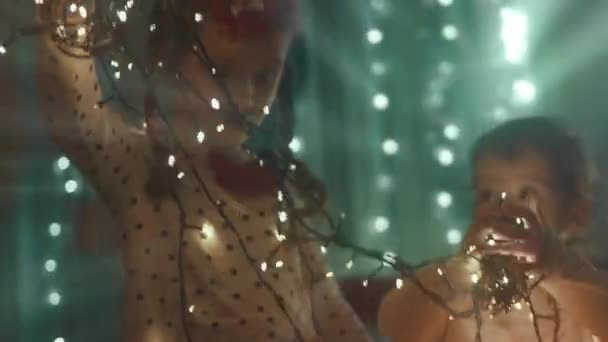 家家户户装饰他们的圣诞假期 美丽快乐的女孩有乐趣与灯玩耍和拥抱 圣诞快乐 节日快乐 快乐的家庭时光 — 图库视频影像