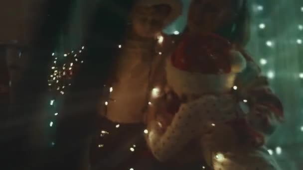 家族はクリスマス休暇のために家を飾る 美しい幸せな女の子はライトと抱擁で遊ぶのを楽しんでいます メリークリスマスとハッピーホリデー 幸せな家族の時間 — ストック動画