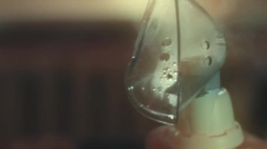 Güzel küçük kız kanepede otururken kompresör spreyiyle solunum yapıyor. Beş yıl oldu. Yüzünde nebulizör maskesiyle salin buharı soluyan bir kız. Anne kızının nefes almasına yardım ediyor.