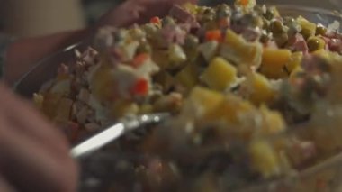 Beyaz tabakta Olivier salatası, rendelenmiş yumurta ile süslenmiş. Geleneksel Yeni Yıl ve Noel Rus salatası. Yakın çekim, 4K video. Yavaş çekim.