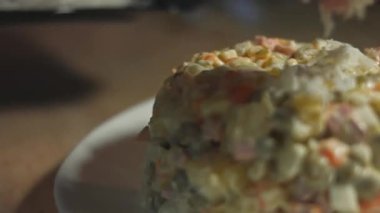 Beyaz tabakta Olivier salatası, rendelenmiş yumurta ile süslenmiş. Geleneksel Yeni Yıl ve Noel Rus salatası. Yakın çekim, 4K video. Yavaş çekim.