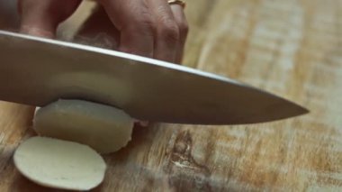 Ahşap bir kesme tahtasında mozarella peyniri dilimleyen kadın elleri. 4K video. Üst görünüm.
