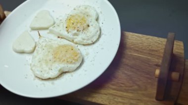 Parmigiano ve mozzarella peynirli kızarmış tavuk yumurtası, kalp şeklinde. Bardakta sıcak kahve ve şekeri karıştırıyorum. Sevgililer Günü 'nde sevdiklerine sürpriz olsun diye yemek. 4K video. Sanatsal