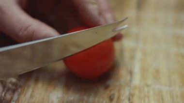 Tahtada mutfak bıçağıyla kırmızı kiraz domateslerini dilimlemek, sevgililer günü için kalp şeklinde pizza hazırlamak. 4K video.