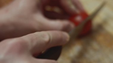 Tahtada mutfak bıçağıyla kırmızı kiraz domateslerini dilimlemek, sevgililer günü için kalp şeklinde pizza hazırlamak. 4K video.