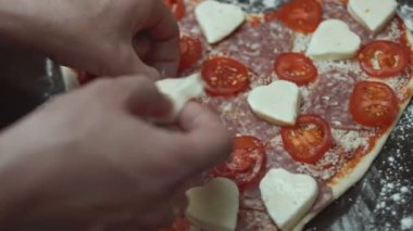 Fırın tepsisinde dilimlenmiş kiraz domatesleri kalp şeklinde pizzaya ekliyorum. Sevgililer Günü için kalp şeklinde pizza hazırlıyorum. Sevdiğim biri için. 4K video. Sanatsal çekim.