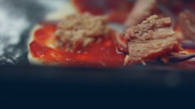 Pizza hamuruna ton balığı serpiştirmek. Sevgililer Günü için kalp şeklinde ton balıklı pizza hazırlıyorum. 4K video. Sanatsal çekim, makro görünüm.