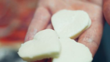 Pizza hamuruna ton balığı serpiştirmek. Sevgililer Günü için kalp şeklinde ton balıklı pizza hazırlıyorum. 4K video. Sanatsal çekim, makro görünüm.