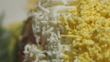 Beyaz tabakta Olivier salatası, rendelenmiş yumurta ile süslenmiş. Geleneksel Yeni Yıl ve Noel Rus salatası. Yakın çekim, 4K video. Yavaş çekim.