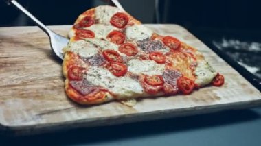 Tahtaya sıcak kalp şeklinde pizza koymak. Sevgililer Günü 'nde sevdiklerine sürpriz yemek. 4K video. Sanatsal çekim.