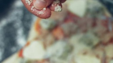 Pizzanın üzerine başka malzemelerle parmesanlı peynir serpiştirmek. Sevgililer Günü için kalp şeklinde ton balıklı pizza hazırlıyorum. 4K video.