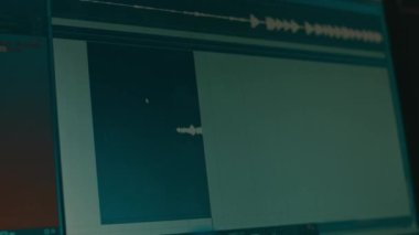 Ses kaydetme ve düzenleme sürecini gösteren monitörün yakın görüntüsü. Mühendis ekranı. Grafik hacmi düzeyi. Kayıt stüdyosunda ışık zayıf.