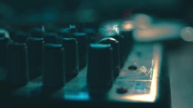 Ses karıştırma konsolunu ayarlayan parmaklar yakın plan. Ses üretimi için kayıt stüdyosunda mikser konsolu. Zayıf ışık.