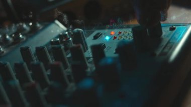 Ses karıştırma konsolunu ayarlayan parmaklar yakın plan. Ses üretimi için kayıt stüdyosunda mikser konsolu. Zayıf ışık.
