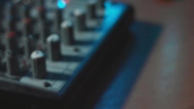 Ses karıştırma konsolunu ayarlayan parmaklar yakın plan. Ses üretimi için kayıt stüdyosunda mikser konsolu. Zayıf ışık.