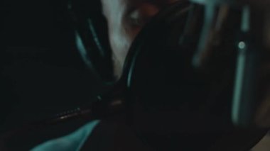 Profesyonel mikrofonlu yakışıklı rap şarkıcısının portresi modern stüdyoda şarkı söylüyor. Müzik prodüksiyonu. Zayıf ışık.