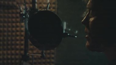 Profesyonel mikrofonlu yakışıklı rap şarkıcısının portresi modern stüdyoda şarkı söylüyor. Müzik prodüksiyonu. Zayıf ışık.