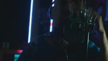 Profesyonel mikrofonlu yakışıklı rap şarkıcısının portresi modern stüdyoda şarkı söylüyor. Müzik prodüksiyonu. Zayıf ışık.