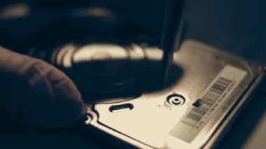 Yakın plan. Tornavida, bilgisayarın sabit diskindeki vidayı söküyor. Erkek eller bilgisayar sabit diskindeki vidayı tornavidayla büker. Bilgisayar sabit diskini onarma ustasının elleri HDD.