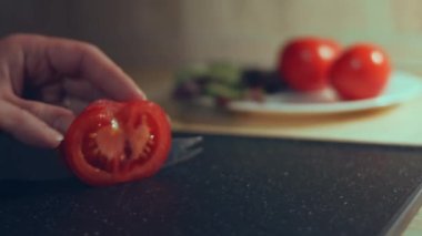 Kadın eli mutfak bıçağıyla kesme tahtasında taze domates kesiyor. Sağlıklı beslenme