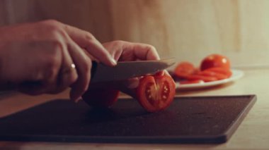 Kadın eli mutfak bıçağıyla kesme tahtasında taze domates kesiyor. Sağlıklı beslenme