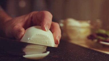 Bir mozarella topunu kesim masasında dilimlemek. Yakın çekim görünümü.