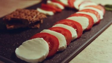 Caprese - İtalyan ulusal yemeği. Noel şeker kamışı şeklinde dilimlenmiş domates ve mozarella. Fesleğen ve zeytinyağıyla servis edilir. Yavaş çekim.