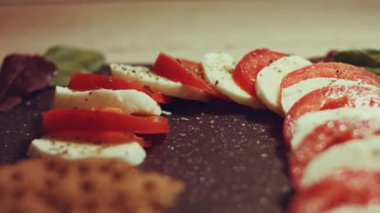 Caprese - İtalyan ulusal yemeği. Noel şeker kamışı şeklinde dilimlenmiş domates ve mozarella. Fesleğen ve zeytinyağıyla servis edilir. Yavaş çekim.