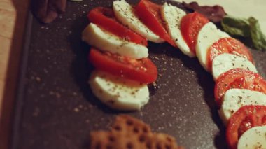 Caprese - İtalyan ulusal yemeği. Noel şeker kamışı şeklinde dilimlenmiş domates ve mozarella. Fesleğen ve zeytinyağıyla servis edilir. Yavaş çekim.
