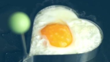 Tavada kalp şeklindeki bir yumurtayı kır. İştah açıcı görünmek için yeni yemek menüleri oluşturun. Yiyecek konsepti.
