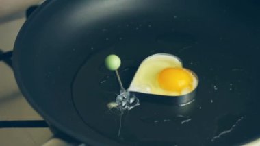 Tavada kalp şeklindeki bir yumurtayı kır. İştah açıcı görünmek için yeni yemek menüleri oluşturun. Yiyecek konsepti.