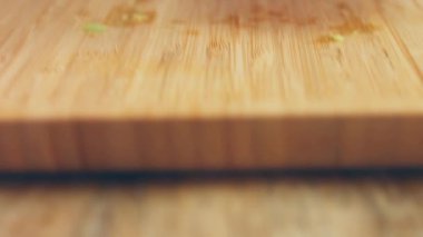 Siyah eldivenli bir şef ahşap bir masada avokado soyar ve keser.