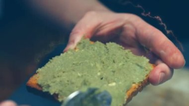 Sağlıklı vegan avokado tostu hazırlıyorum. Çavdar ekmeğine yapışmış avokado ezmesi, yakın çekim.