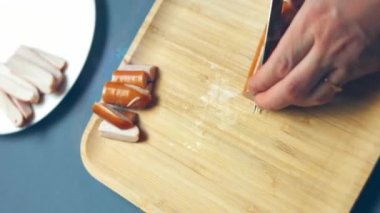 Et sosislerini bıçakla kesmek, sosisleri seramik bıçakla kesmek, Şef sosisleri pişirme bıçağıyla kesiyor, sosisleri yakın plan dilimliyor.