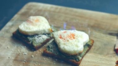 Kırık avokado ve ahşap bir tahtanın üzerinde parmesanlı peynirli tost ekmeği üzerinde kalp şeklinde yumurtalar. 8 Mart 'ta sürpriz kahvaltı hazırlıyorum. Makro görünüm, yavaş çekim