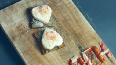 Kırık avokado ve ahşap bir tahtanın üzerinde parmesanlı peynirli tost ekmeği üzerinde kalp şeklinde yumurtalar. 8 Mart 'ta sürpriz kahvaltı hazırlıyorum. Makro görünüm, yavaş çekim