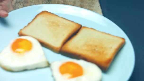 木製の板の上に砕いたアボカドとパルミジャーノチーズとトーストのハート型の卵 3月の驚きの朝食を調理します マクロビュー スローモーション — ストック動画