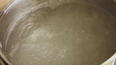 Tencerede sarı çiğ patatesle kaynayan suyun yakın görüntüsü. Genç patates kaynar suda kaynatılır.