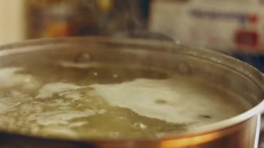 Soyulmuş patatesler Makro 'da kaynar suyla tencereye düşüyorlar.