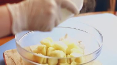 Baharatları ve dilimlenmiş patatesleri cam şeffaf kapta yakın plan çekimde karıştırıyorum.