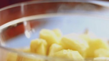 Baharatları ve dilimlenmiş patatesleri cam şeffaf kapta yakın plan çekimde karıştırıyorum.