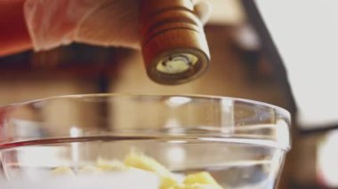 Baharatları ve dilimlenmiş patatesleri cam şeffaf kapta yakın plan çekimde karıştırıyorum.