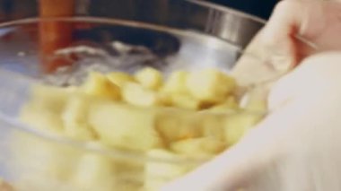 Baharatları ve dilimlenmiş patatesleri cam şeffaf kapta yakın plan çekimde karıştırıyorum.